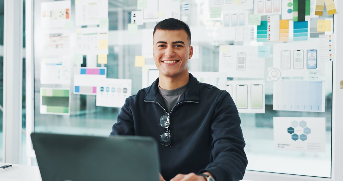 Web designer smiling while working on a laptop in a modern office